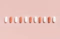 Mix of medical capsules in a line on light pink top view. Dietary supplements Royalty Free Stock Photo