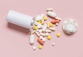 Mix of medical capsules and pills with a bottle on light pink top view. Medicinal treatment Royalty Free Stock Photo