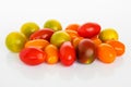 Mix of multicolored cherry tomatoes on a white glossy background. Heap of yellow, orange and red small tasty tomatoes. Vegetarian
