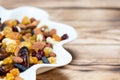 Mix of nuts and berries. Dried fruits in white plate on wooden table, copy space for text. Healthy food and vitamins Royalty Free Stock Photo