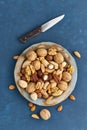 Mix of nuts on plate - walnut, almonds, pecans, macadamia. Healthy vegan food. Clean eating, balanced diet. Blue bright table,