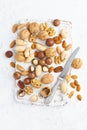 Mix of nuts - walnut, almonds, pecans, macadamia and knife for opening shell on white wooden cutting board. Healthy vegan food.