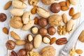 Mix of nuts - walnut, almonds, pecans, macadamia and knife for opening shell on white wooden cutting board. Healthy vegan food.