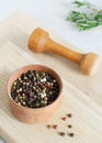 Mix peppercorns black, white, red and allspice in a wooden pestle with a chime for a mortar on a light background. Royalty Free Stock Photo