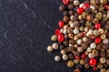 Mix of peppercorns on a dark stone background