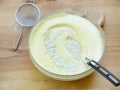 Mix pounded chicken egg yolks with the sugar, beaten egg whites and wheat flour in a glass bowl on a wooden background. Royalty Free Stock Photo