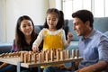 Mix race family lovers, Caucasian dad and Asian mom with half-blood daughter playing wooden domino game together in living room Royalty Free Stock Photo