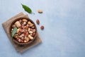 A mix of raw nuts in a wooden bowl on old burlap on a blue background Royalty Free Stock Photo