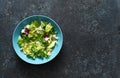 Mix salad. Green lettuce leaves in a blue keyring on a stone blue background. view from above