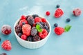 Mix of summer frozen berries in a white bowl on a blue concrete background. Copy space Royalty Free Stock Photo