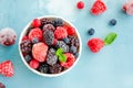 Mix of summer frozen berries in a white bowl on a blue concrete background. Copy space Royalty Free Stock Photo