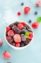 Mix of summer frozen berries in a white bowl on a blue concrete background. Copy space Royalty Free Stock Photo