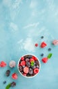 Mix of summer frozen berries in a white bowl on a blue concrete background. Copy space Royalty Free Stock Photo