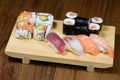 Mix of sushi, sushi roll and nigiri with salmon, tuna, sea bass, shrimp, avocado served on a wooden plate Royalty Free Stock Photo