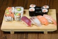 Mix of sushi, sushi roll and nigiri with salmon, tuna, sea bass, shrimp, avocado served on a wooden plate Royalty Free Stock Photo