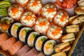 Mix of sushi rolls with salmon, avocado, smocked eel, tobiko caviar in delivery box on black background Royalty Free Stock Photo