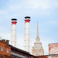 Mix of two pipes and buildings of different times against blue sky. Old Industrial building of the factory from red Royalty Free Stock Photo