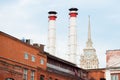 Mix of two pipes and buildings of different times against blue sky. Old Industrial building of the factory from red Royalty Free Stock Photo