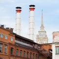 Mix of two pipes and buildings of different times against sky. Old Industrial building of factory from red brick Royalty Free Stock Photo