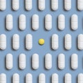 Mix of white medical pills in a line with one yellow on light blue top view. Dietary supplements Royalty Free Stock Photo