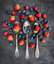 Mixed berries laying in three spoons with berries around the spoons Royalty Free Stock Photo