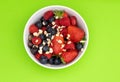 Mixed berries strawberries blueberries and raspberries served in a white bowl. Cropped photo against green background. oatmeal as Royalty Free Stock Photo