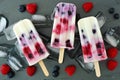 Mixed berry yogurt popsicles on a slate background