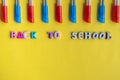 Mixed blue and red ballpoint pens on yellow background from above. Inscription from colored letters back to school. Flat lay