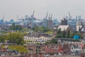 Mixed classic architecture of Rotterdam leafy urban apartment buildings in foreground with harbour waterfront port cranes in backg