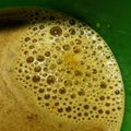 Mixed coffee is brown with foam after shaking, in a green glass
