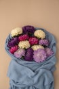 Mixed colorful flowers in cotton blue sweater. Creative minimalistic flowers. Concept of holiday celebrating present and