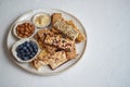 Mixed composition of energy nutrition bar, granola on ceramic plate over white background