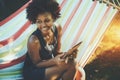 Mixed curly teenage female with digital tablet in hammock