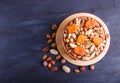 Mixed different kinds of nuts in ceramic bowl on black wooden background with copy space Royalty Free Stock Photo