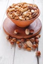 Mixed different kinds of nuts in ceramic bowl on white wooden background Royalty Free Stock Photo