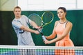 Mixed Doubles player hitting tennis ball, partner standing near net Royalty Free Stock Photo