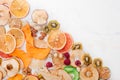 Mixed dried fruit and vegetable chips, candied pumpkin slices, nuts and seeds on white marble background Royalty Free Stock Photo