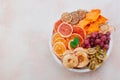 Mixed dried fruit and vegetable chips in round ceramic plate on beige concrete background