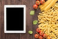 Mixed dried pasta selection and tablet on wooden background