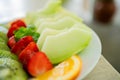 mixed fruit plate containing melon, strawberries, oranges and kiwi. The main focus is on melons Royalty Free Stock Photo