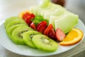 mixed fruit plate containing melon, strawberries, oranges and kiwi. Main focus on strawberry Royalty Free Stock Photo