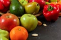 Mixed fruits and vegetables - red peppers, avocado, apples, pears, tangerines, pecan nuts, almonds and pumpkin seeds on black Royalty Free Stock Photo