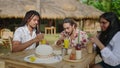 Group of lgbtq friends enjoy tropical drinks at beach hut. Mixed gender pals laugh, share stories, savor summer day