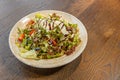 Mixed green salad with shaved parmesan cheese served on wooden table