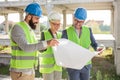 Group of architects or business partners discussing floor plans on a construction site Royalty Free Stock Photo