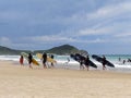 Mixed group of surfers looking out to sea with their colorful boards on a beautiful sunny summer day with the blue sky Royalty Free Stock Photo