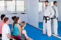 Mixed group of trainees listens to the karate coach