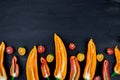 Mixed of half red and yellow pepper with a green branch near cherry tomato on black backround. Top view. Frame. Copy space. Royalty Free Stock Photo