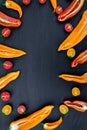 Mixed of half red and yellow pepper with a green branch near cherry tomato on black backround. Top view. Frame. Copy space. Royalty Free Stock Photo