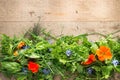 Mixed Leaves and Edible Flowers on Light Wooden Background